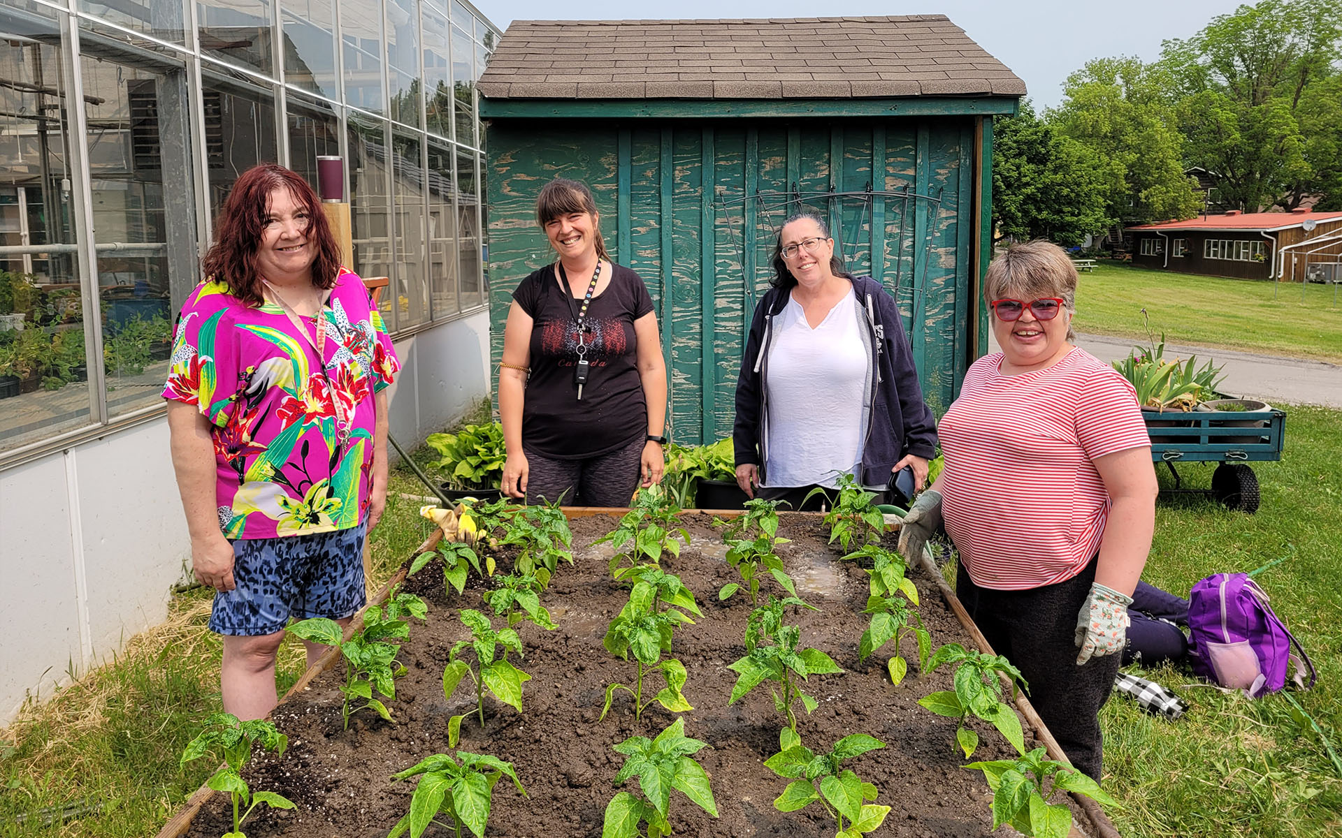 Four women standing at their raised garden bed.